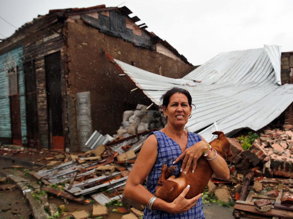 Una mujer posa junto a su casa destruida por el huracán Irma en Cuba