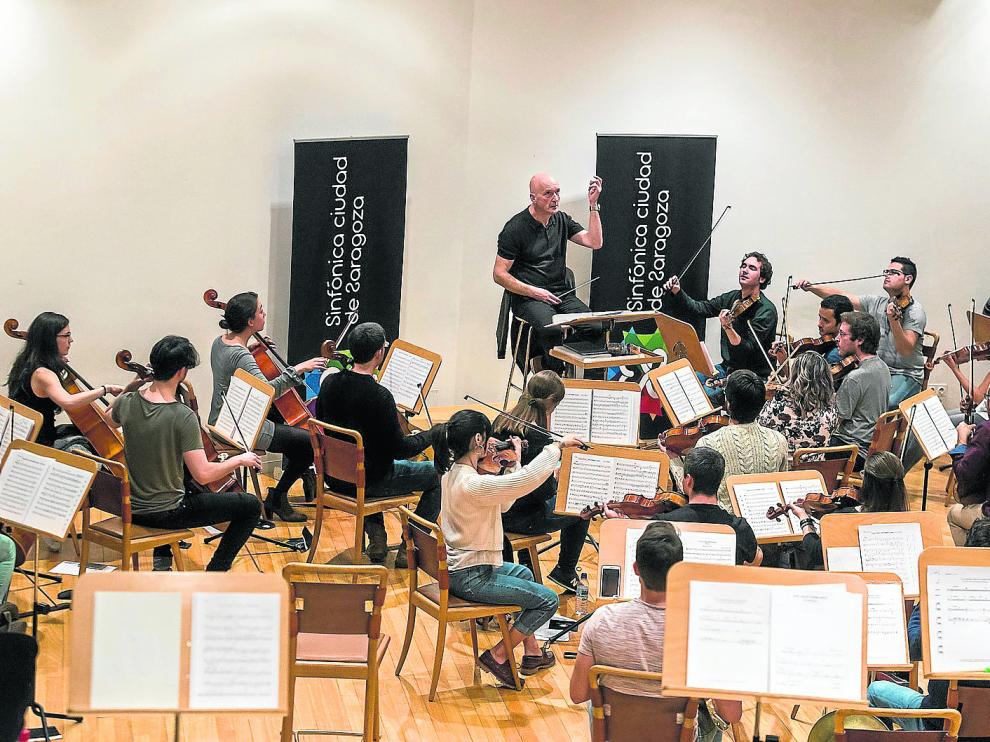 El director Juan Luis Martínez y los músicos de la Sinfónica Ciudad de Zaragoza, durante el ensayo de ayer.