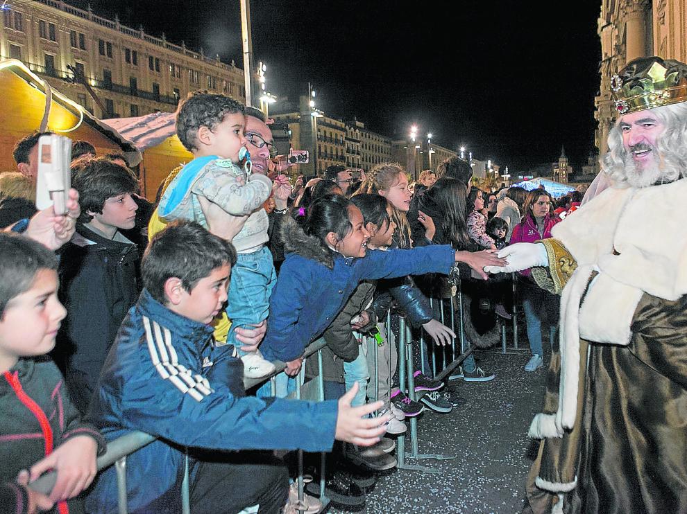 Numeroso público esperaba a Sus Majestades en la plaza del Pilar. En la imagen, el rey Melchor saluda a un grupo de niños que llevaba dos horas esperando.