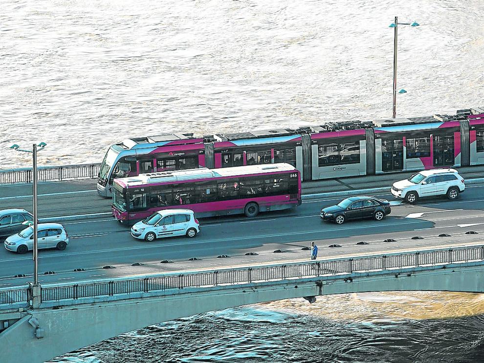 Un autobús y un tranvía recorren en paralelo el puente de Santiago.