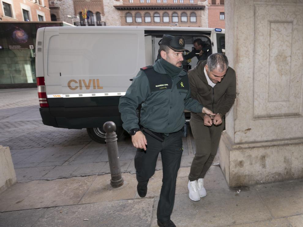 Uno de los detenidos, esposado, es conducido por la Guardia Civil desde el furgón de seguridad al Juzgado