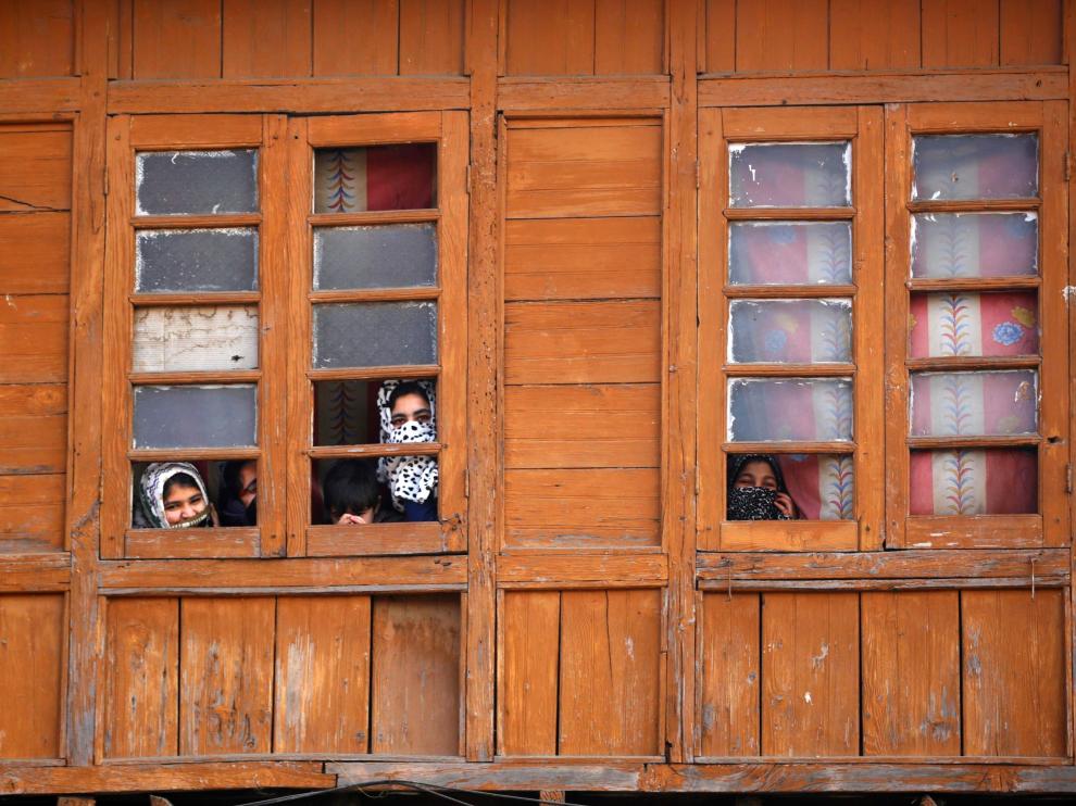 Varias mujeres miran por una ventana en la Cachemira india