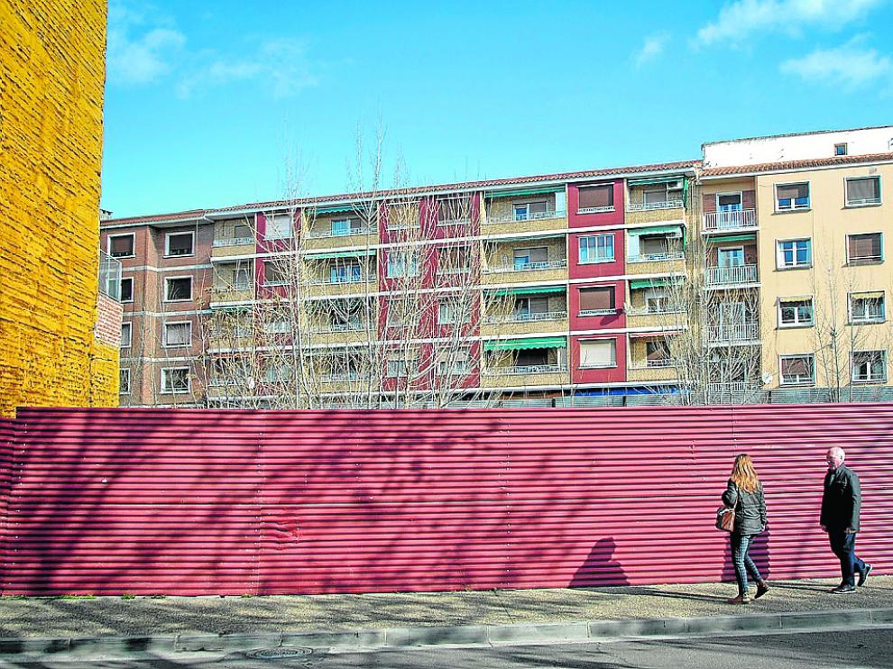 Dos personas pasan junto a la valla que protege el solar de la desaparecida Casa Azul de Calatayud.
