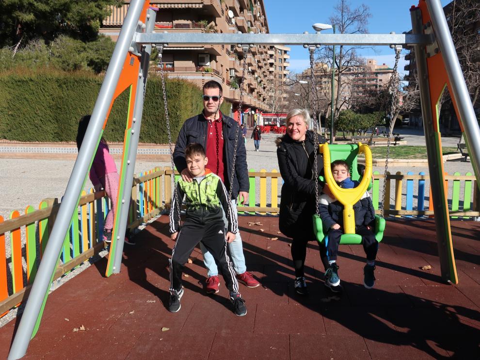 Lizer, en el nuevo columpio adaptado del parque de la Aljafería, con sus padres y su hermano.