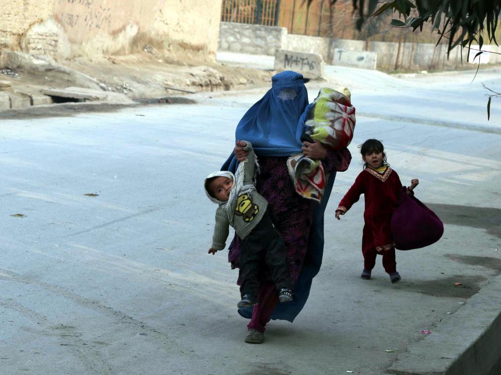 Una mujer huye con tres niños de la zona atacada.