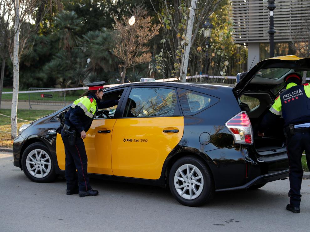 Dos Mossos miran el matetero de un taxi en el exterior del Parlament de Cataluña, en Barcelona.