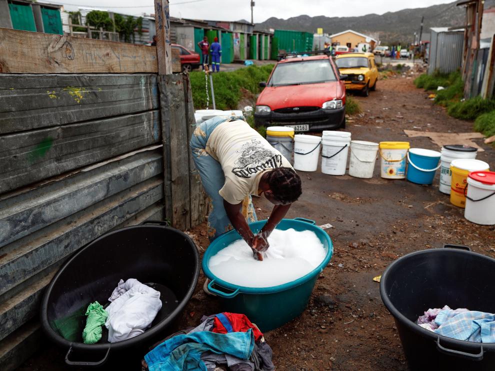 Una mujer lava su ropa con agua recolectada de un grifo comunitario
