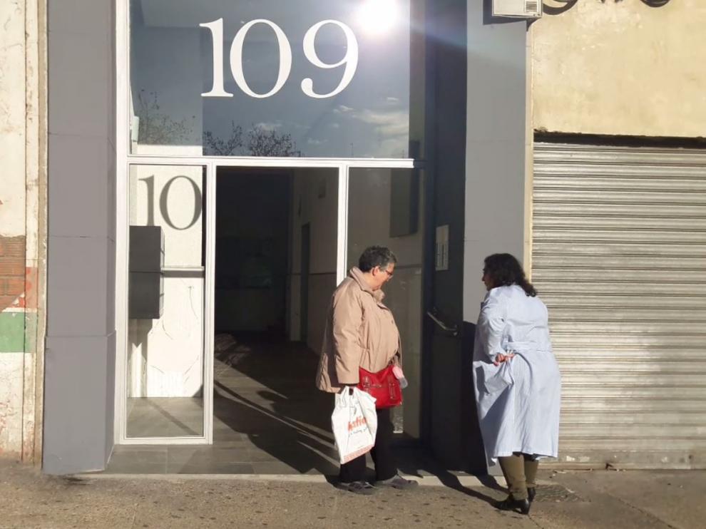 Dos vecinas observan la puerta robada en el número 109 de la calle Miguel Servet, en Zaragoza.