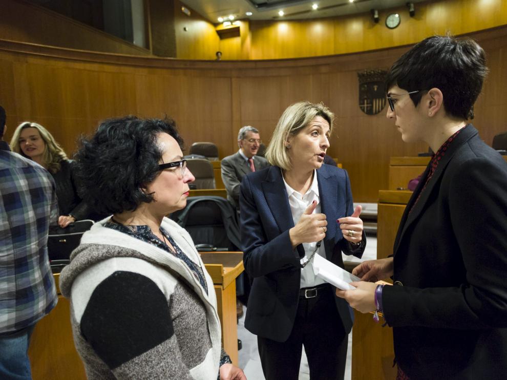 La coordinadora de la ponencia de la ley de renta básica, Pilimar Zamora, entre las diputadas de Podemos Amparo Bella y Violeta Barba, en el pleno.