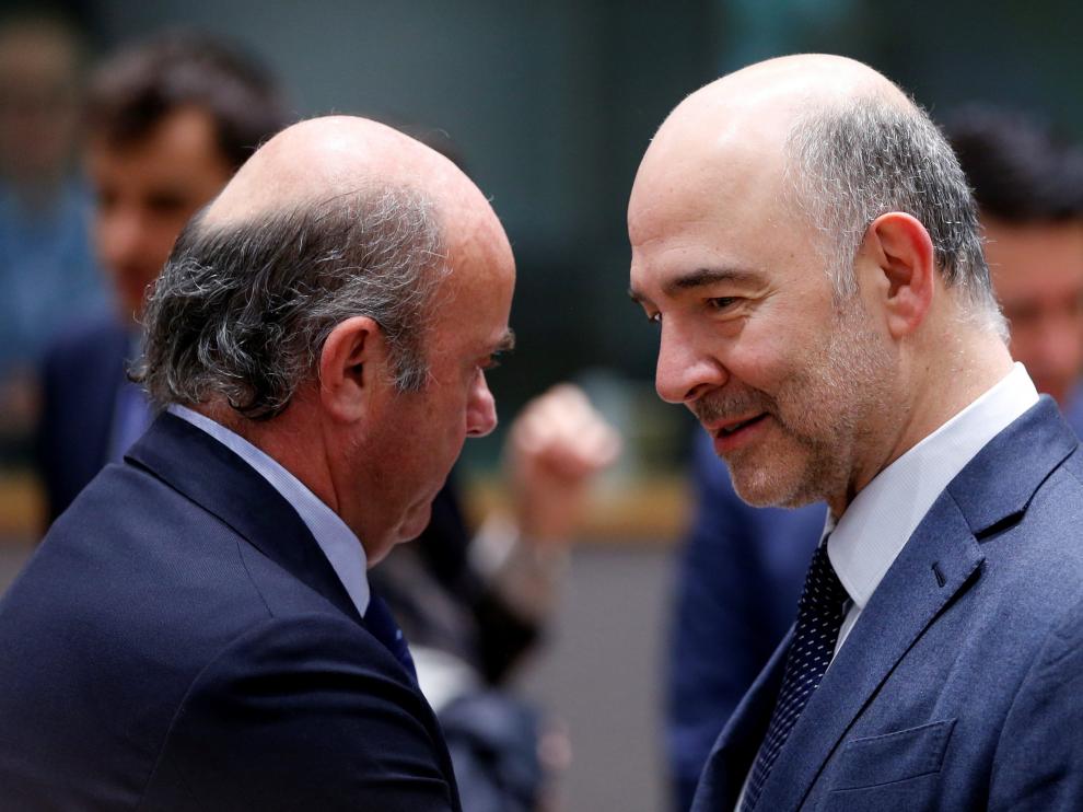 El comisario europeo de Asuntos Económicos, Pierre Moscovici, da la enhorabuena a Luis de Guindos tras su nombramiento como vicepresidente del BCE.