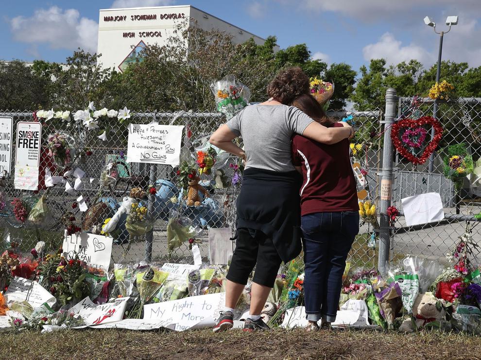 Dos personas mirando el memorial en homenaje a los 17 asesinados en el tiroteo.
