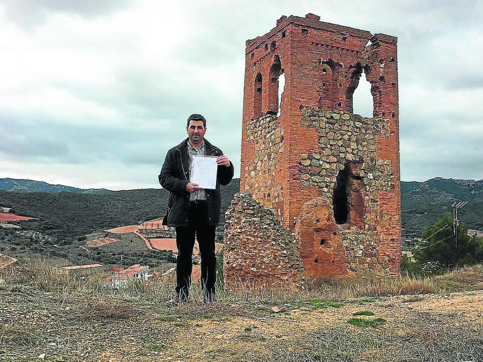 El alcalde de Cosuenda, Óscar Lorente, muestra las escrituras del terreno, junto a la torre.