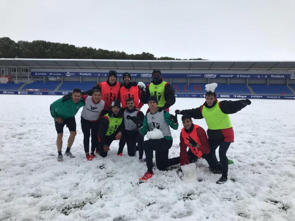 Varios jugadores del Huesca posando sobre un Alcoraz lleno de nieve tras acabar este miércoles el entrenamiento.
