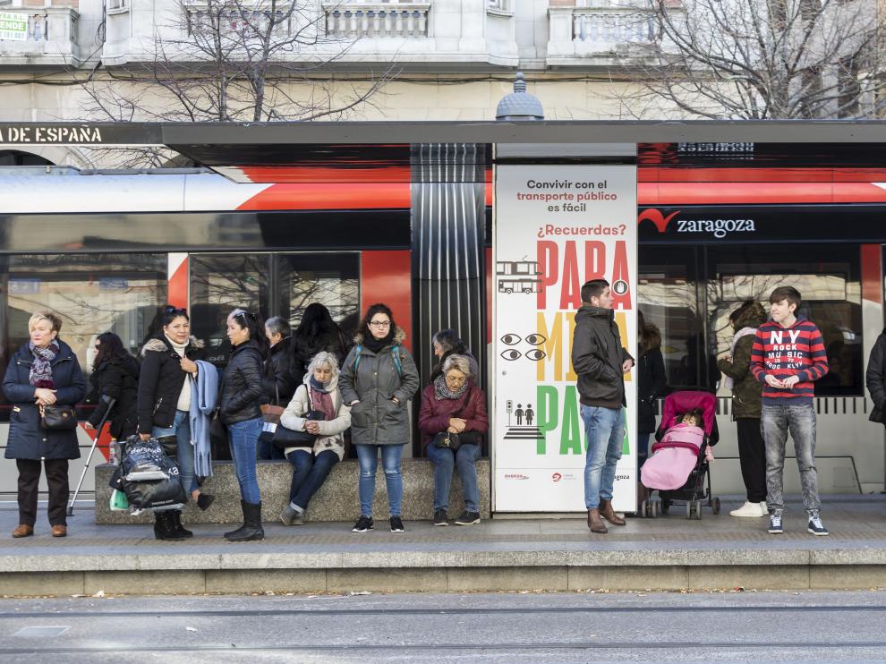 Varios viajeros esperan la llegada del tranvía en la parada del paseo de la Independencia.