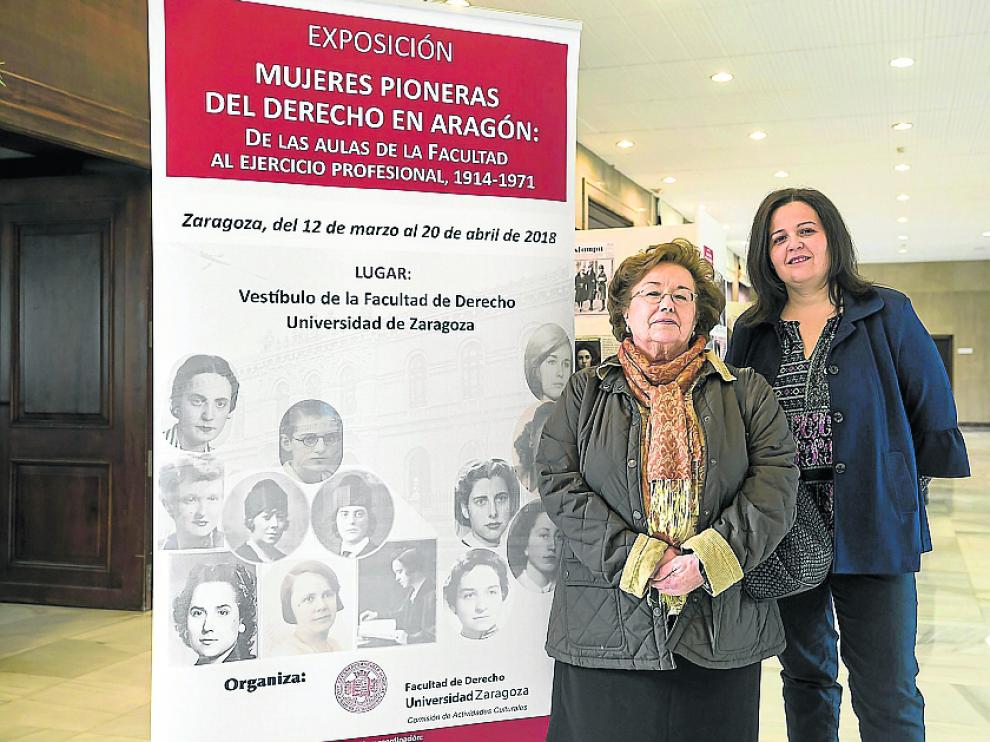Carmen Teresa Aguelo y Belén Causapé junto al cartel que anuncia la exposición en la Facultad de Derecho