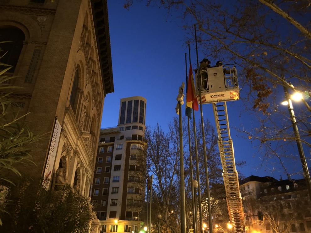 Los bomberos bajan a mitad de asta las banderas frente al Paraninfo.
