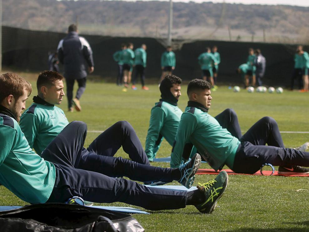 Algunos jugadores del Huesca realizan ejercicios de estiramiento durante un entrenamiento.