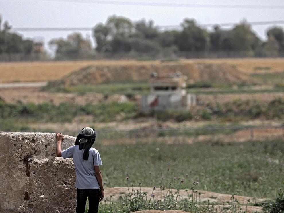 Un niño palestino observa una torre militar israelí días antes de la protesta 'La Marcha del Retorno' en la frontera de Gaza
