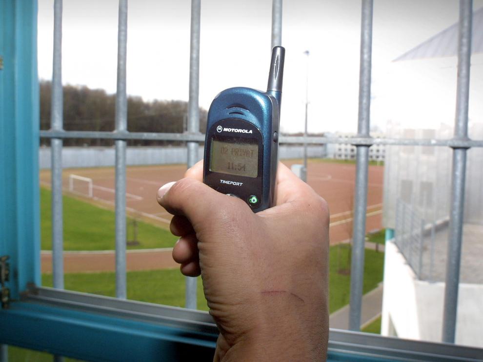 Un preso muestra un teléfono móvil dentro de una celda de una cárcel alemana.