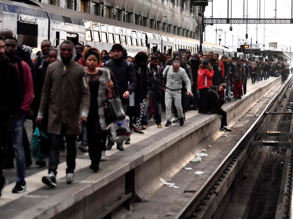 Los pasajeros esperan sentados o caminando por las vías en el primer día de huelga ferroviaria