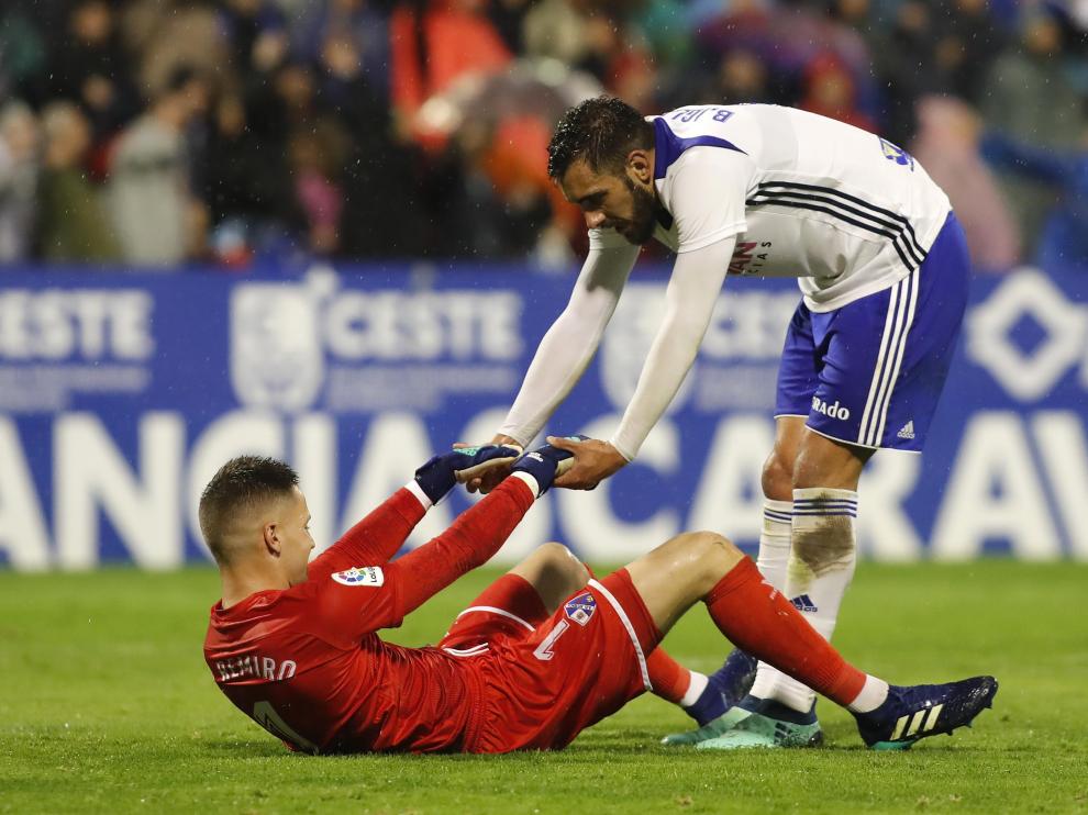 Borja Iglesias, delantero del Real Zaragoza, ayuda a Álex Remiro, portero del Huesca, en el último derbi aragonés.