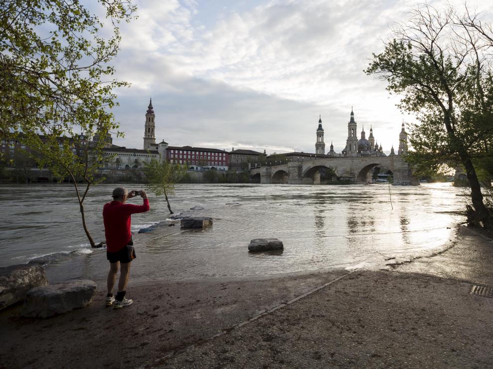 Un zaragozano fotografía el caudal del Ebro a su paso por Zaragoza