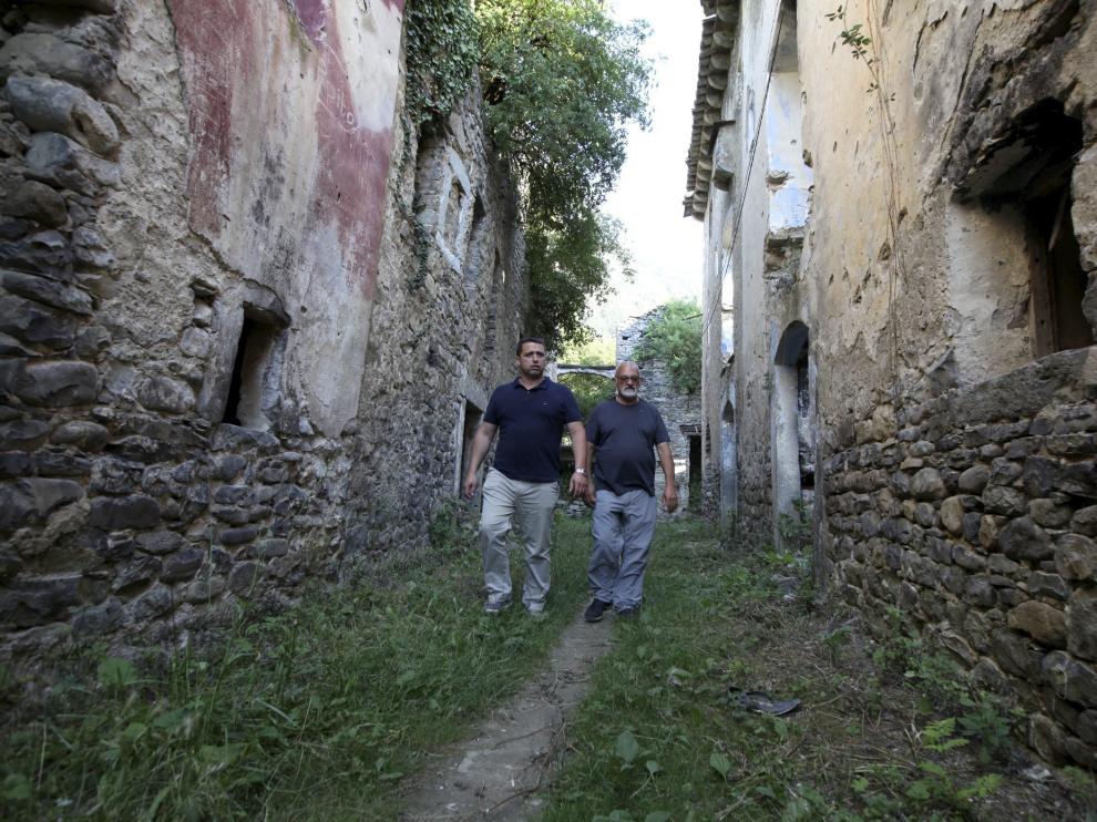 El alcalde de Fiscal, Manuel Larrosa, y Jesús Garcés, uno de los afectados, en las calles de Jánovas, con las casas en ruinas