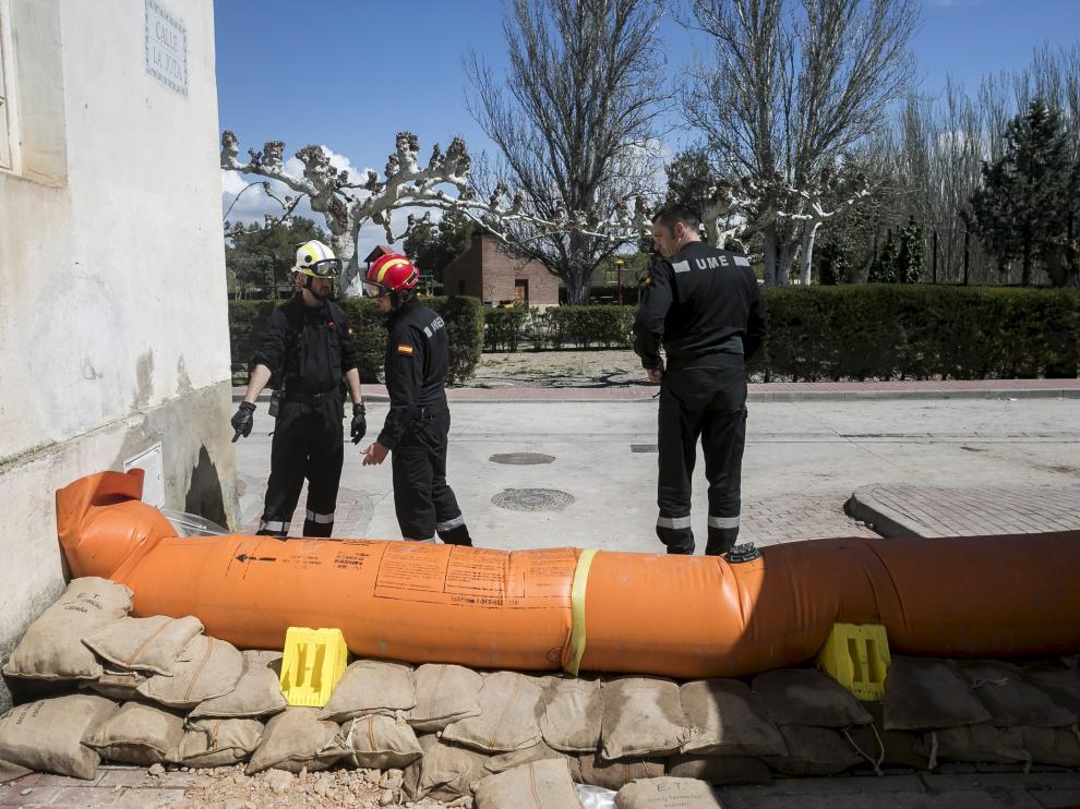 Un vecino de Novillas sortea unas de las barreras de contención que la UME colocó el viernes en la localidad para evitar que el agua entrara en el casco urbano.