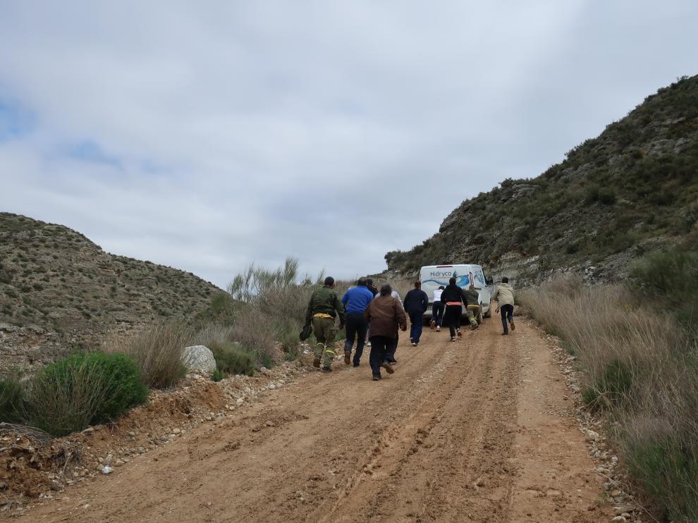 El alcalde, varios vecinos y los agentes ayudan a empujar una furgoneta atascada.
