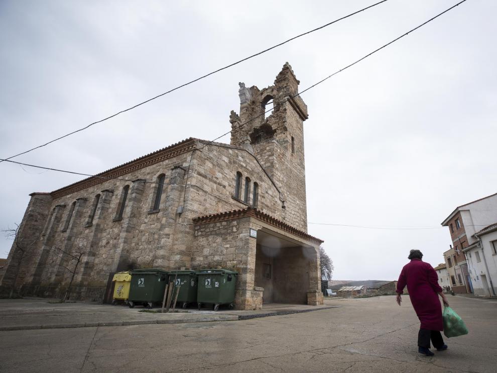 Una vecina cruza delante de la iglesia de Santiago y la torre contigua.
