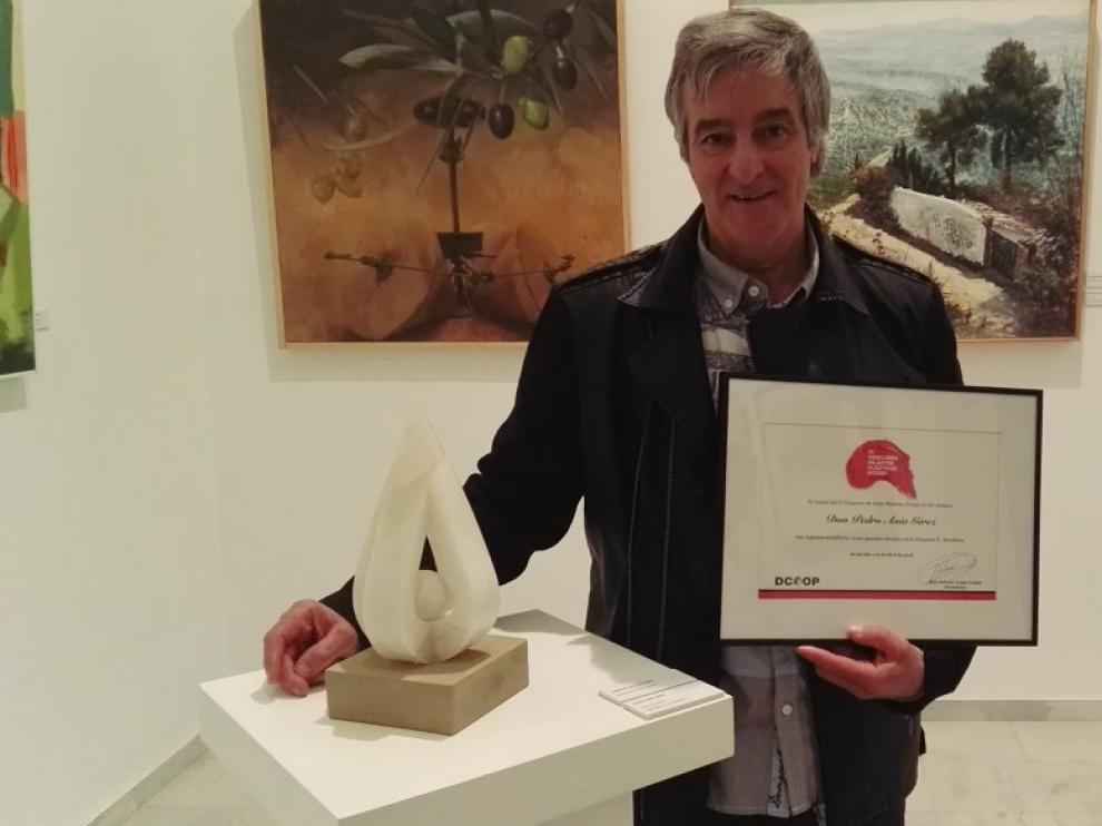 El escultor posa con la obra creada y el diploma recibido.