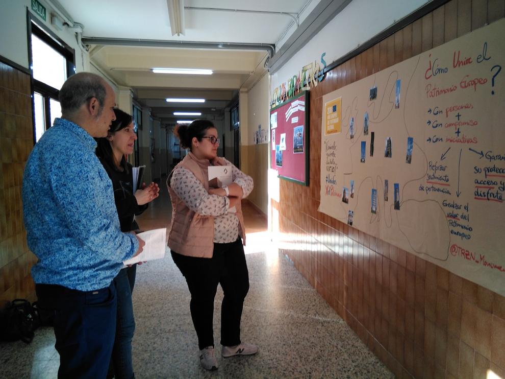 El director del instituto y dos técnicos de Tarazona Monumental frente al mural que recuerda el Día del Patrimonio en el centro escolar
