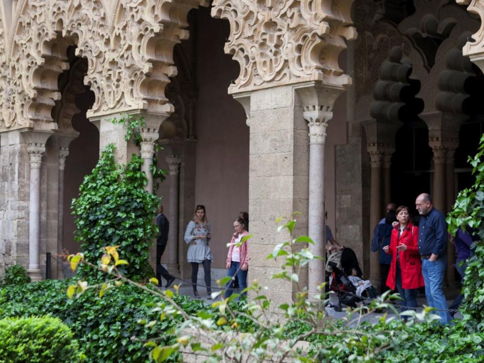 Visitantes bajo los arcos de patio central del palacio de la Aljafería, en Zaragoza.