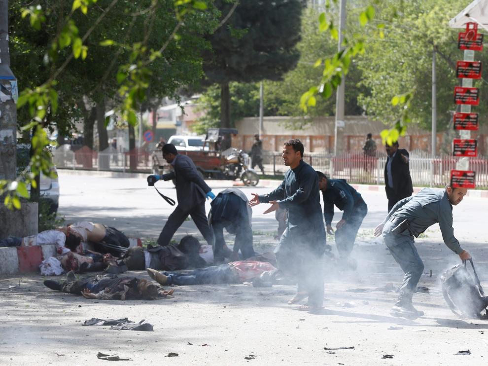 Un policía ayuda a periodistas víctimas de la segunda explosión en Kabul
