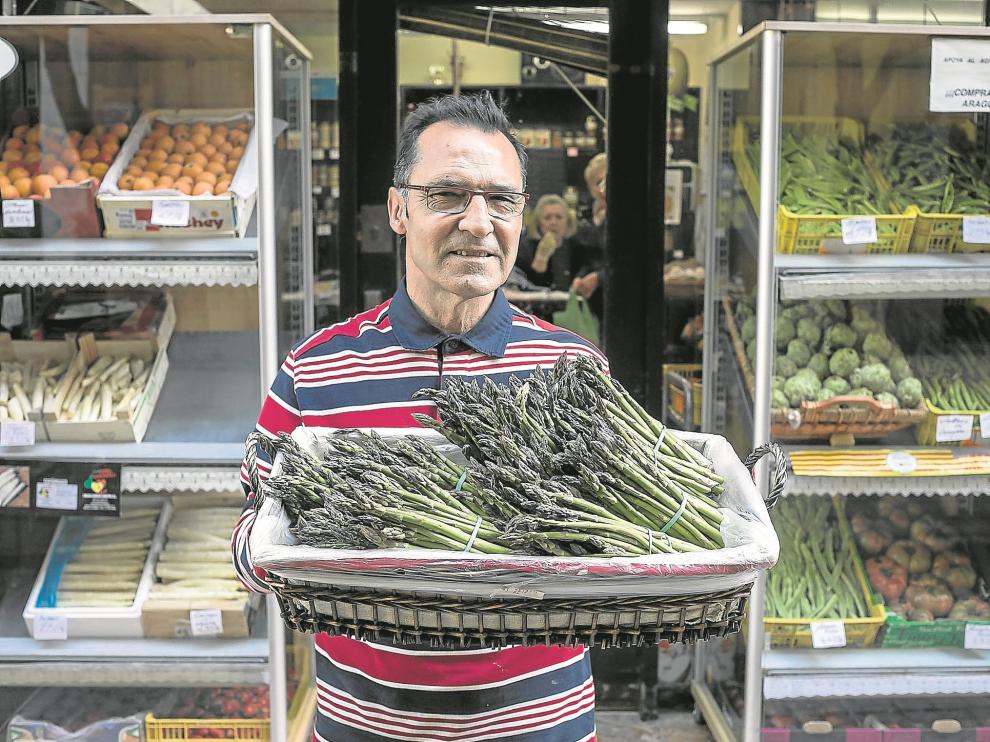El propietario de Frutas Jesús, Jesús Aranda, a las puertas de su local con una bandeja de espárragos, en Zaragoza.