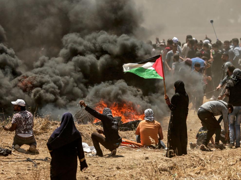Una mujer palestina sostiene una bandera en medio de las protestas
