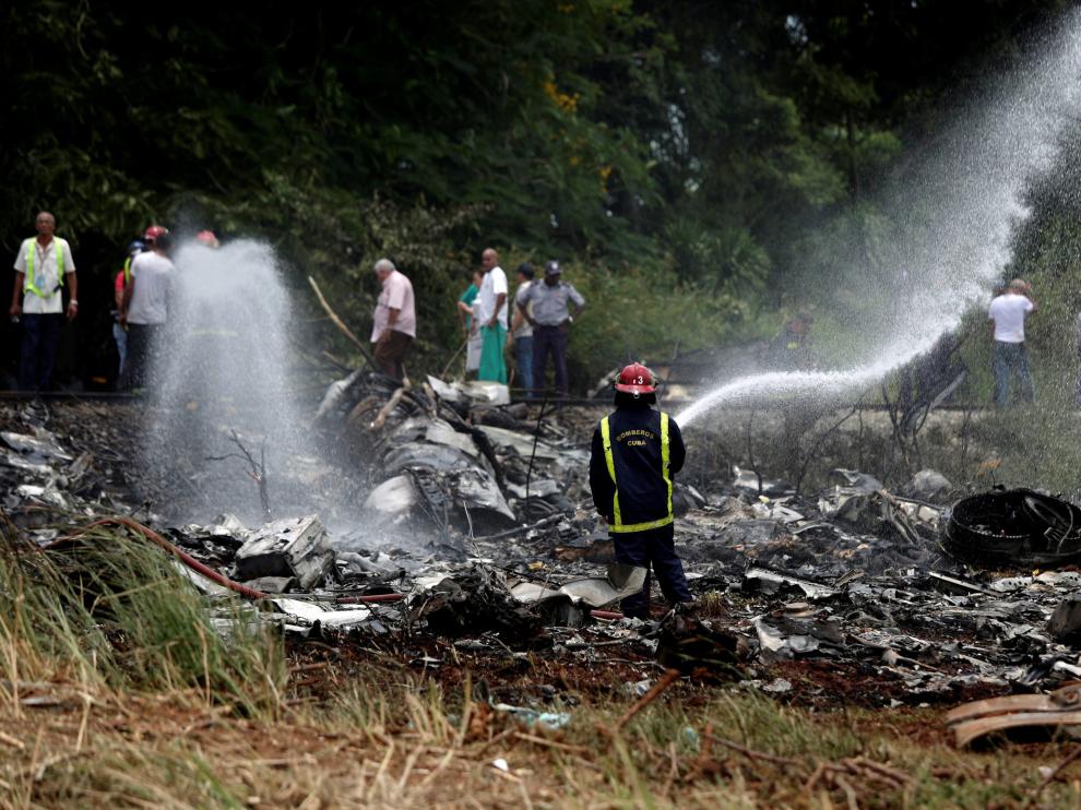 Un bombero refresca la zona donde se estrelló el avión