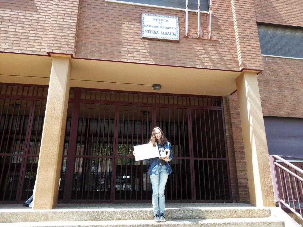 La zaragozana Estela Bescós, alumna del IES Medina Albaida de Zaragoza, posa con su diploma y el trofeo a las puertas del centro.