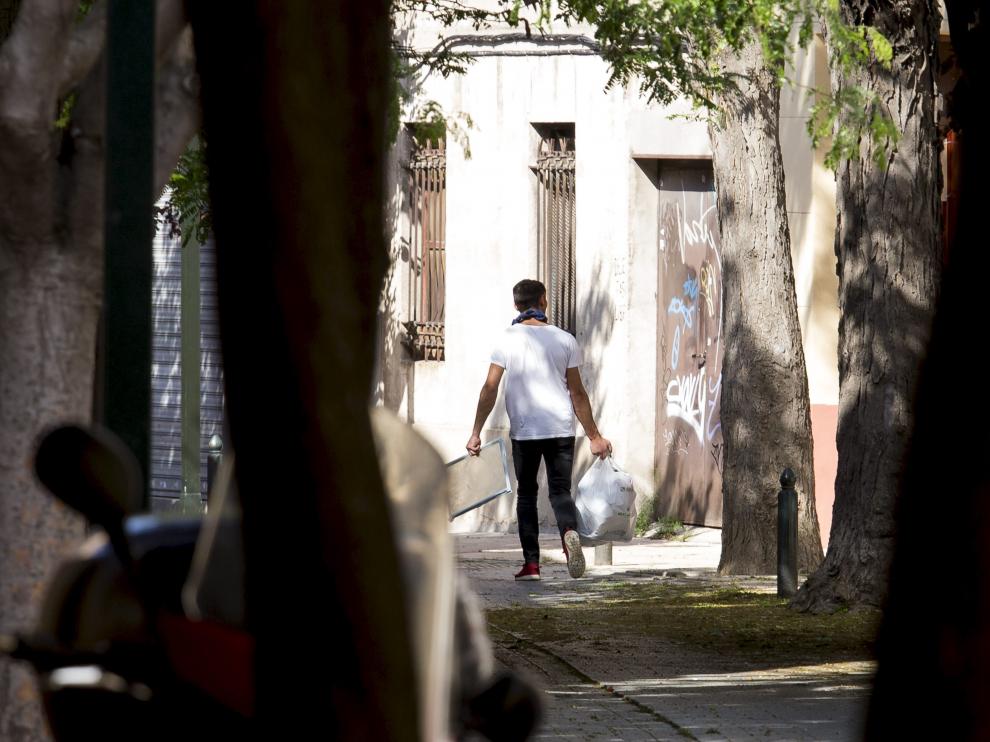 Un joven, ayer, sacando una bolsa de basura de la vivienda en la que vivía el fallecido.