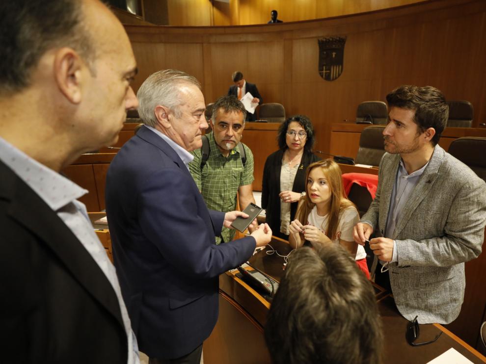 Nacho Escartín, a la derecha, habla con el socialista Javier Sada antes de comenzar el pleno de este jueves