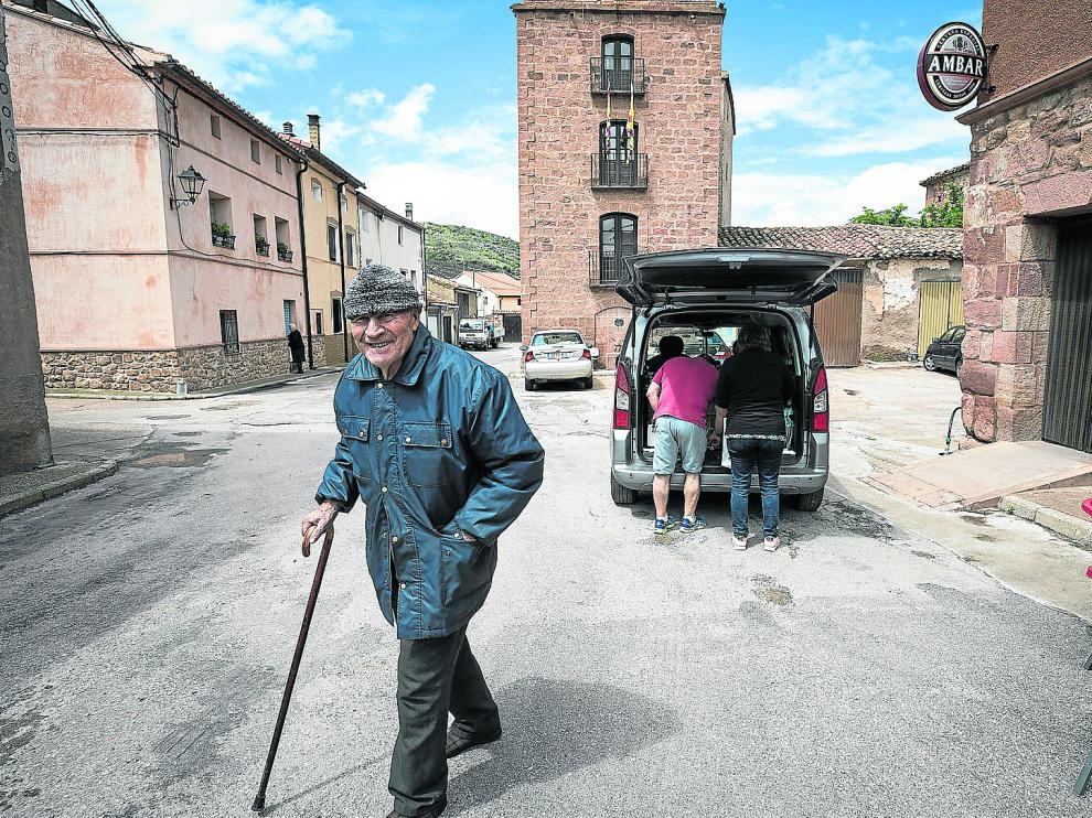 Un vecino de Villar del Salz sonríe a cámara con el ayuntamiento (el más estrecho de la provincia de Teruel) al fondo.