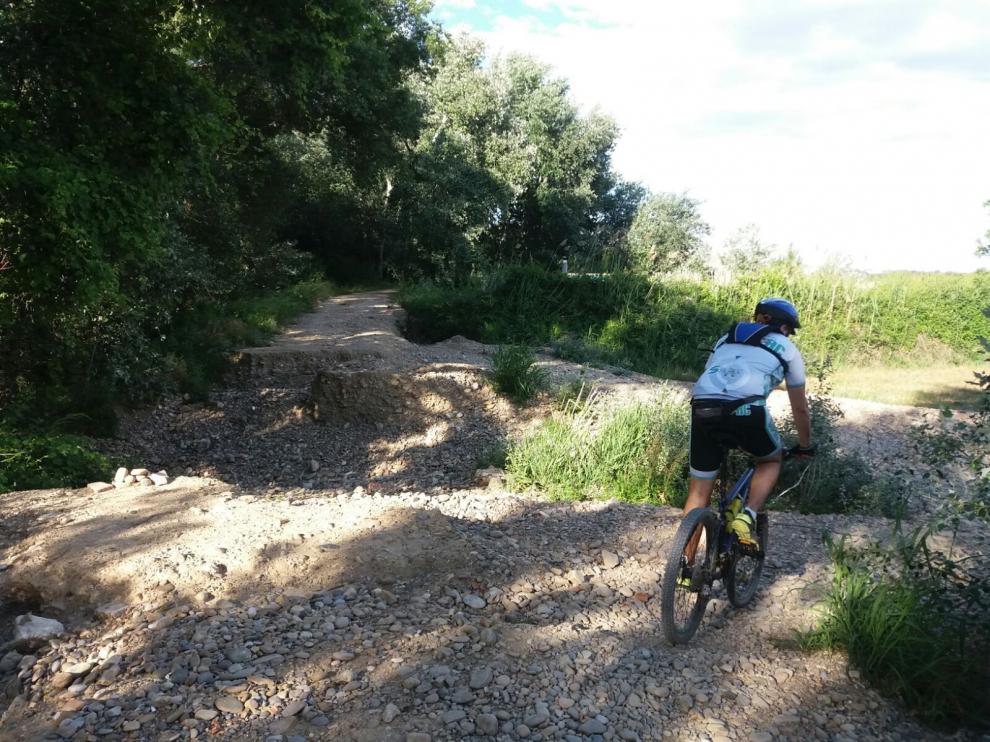 Un ciclista, ante un socavón que atraviesa el camino.