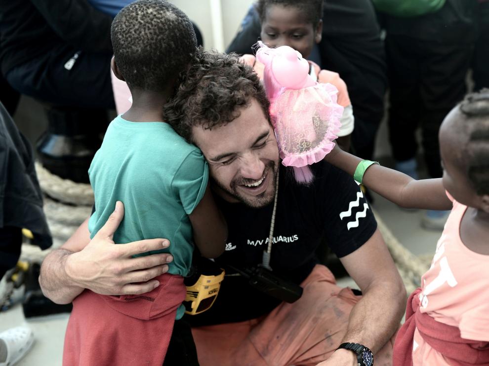Un miembro de la tripulación del Aquarius abraza a varios niños del barco.