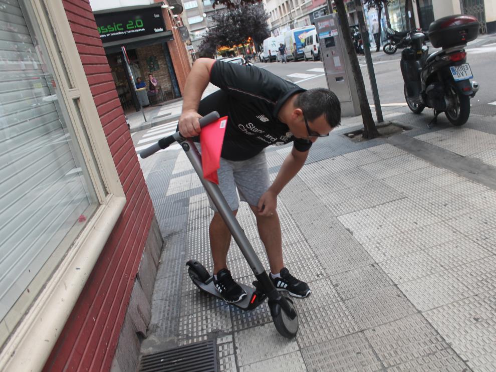 Alin Manda (con los papeles de la denuncia en la mano) muestra su patinete (de la marca Segway), averiado tras el accidente.
