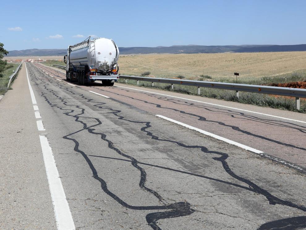 Un camión circula por la N-211 a la altura de Monreal del Campo, con el firme lleno de grietas rellenadas con alquitrán.