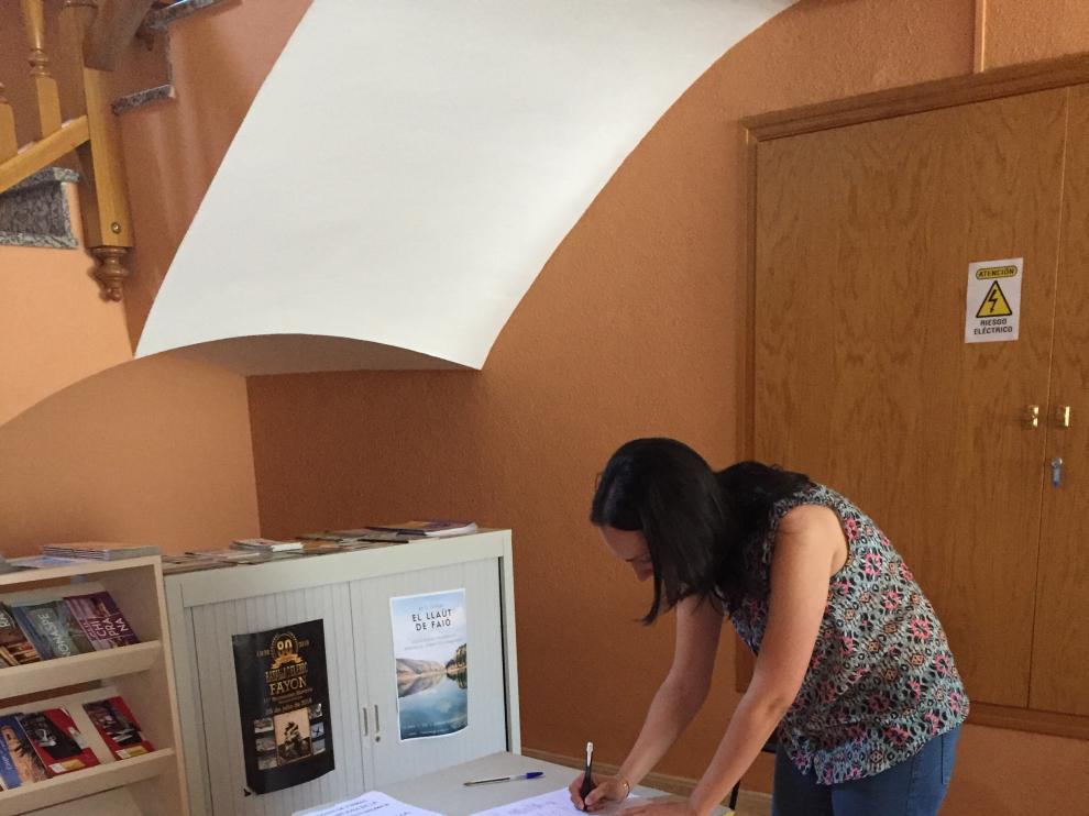 Una vecina firma en la mesa instalada en el ayuntamiento de Fayón.
