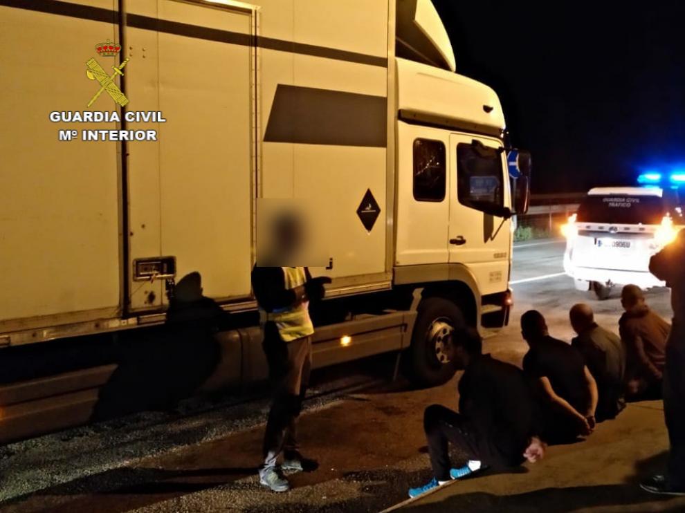 Varios de los detenidos, sentados en el suelo y vigilados por agentes de la Guardia Civil y la Policía Nacional.