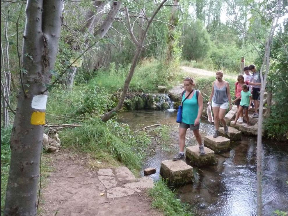 Un grupo de senderistas atraviesa un paso en la senda fluvial del río Alcalá, en la sierra de Gúdar.