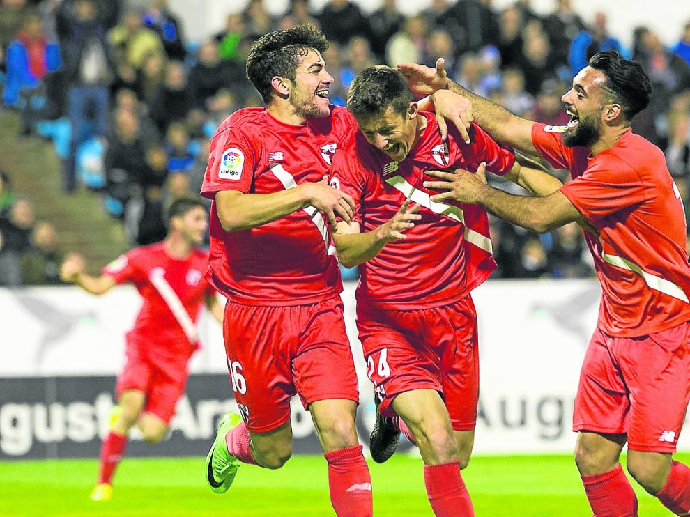 Marc Gual, en el centro, recibe la felicitación de dos compañeros del Sevilla Atlético tras marcar hace un año en La Romareda.