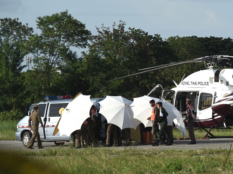 Miembros del ejército y de la policía cubren con paraguas el helicóptero en el que son evacuados los niños